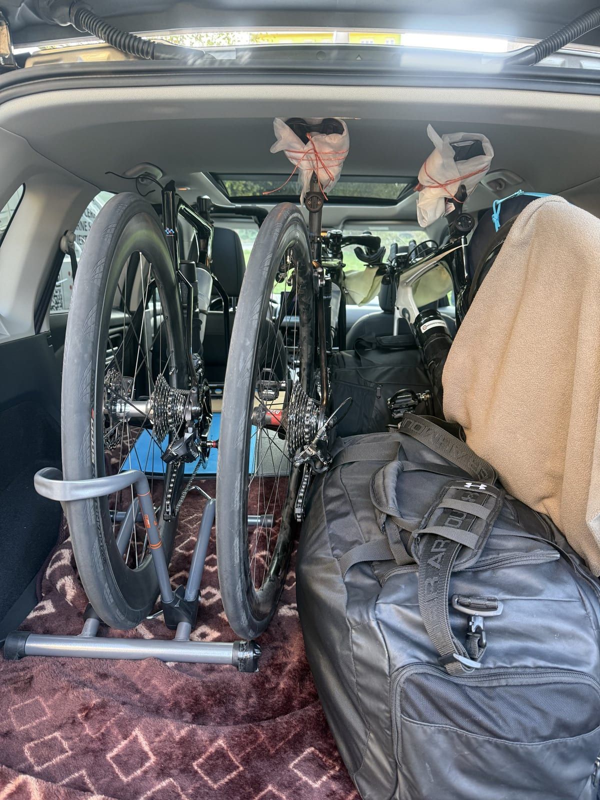 Tri cestné bicykle v stojane v kufri X-Trailu, vedľa nich batožina